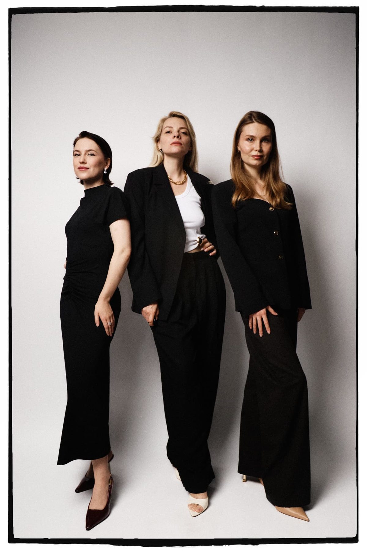 Three women in black outfits posing together